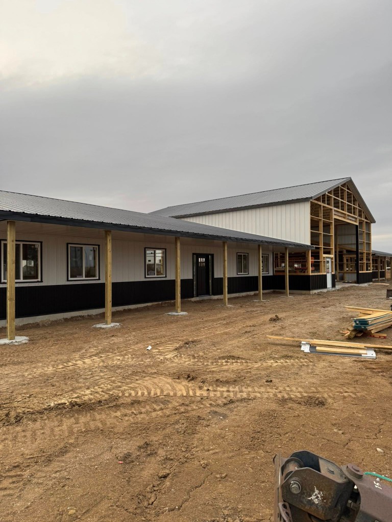 Two-tone siding and porch posts on the living wing; taller shop end still open to framing.