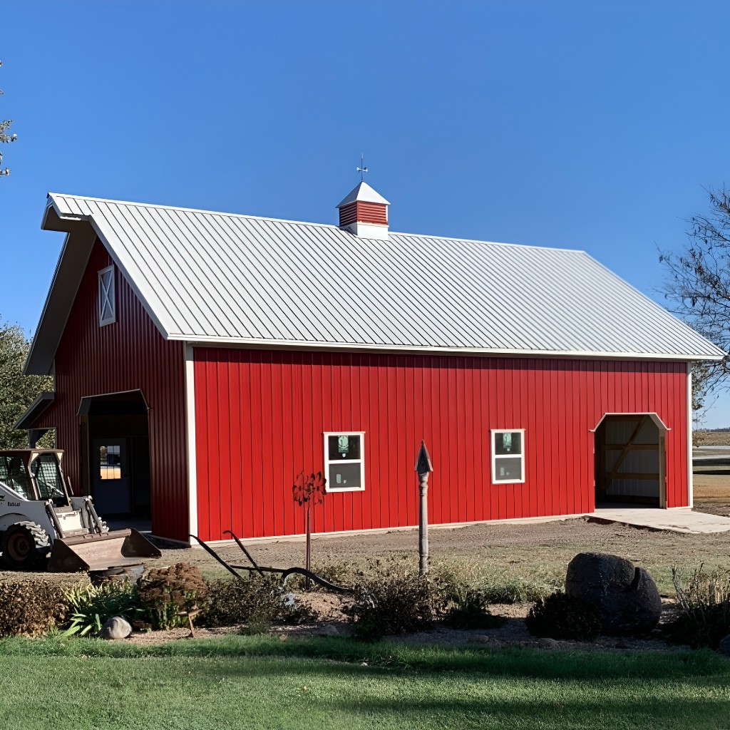 Red post-frame barn with white metal roof, cupola, open and enclosed bays, and landscaped yard—Nebraska farm and pole barn example.