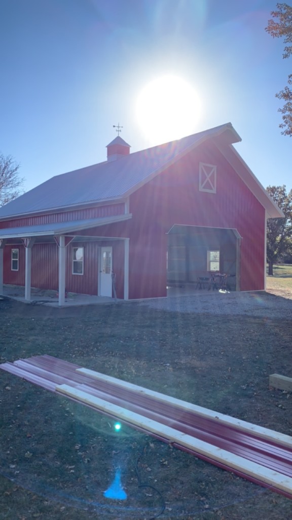 Front gable with open bay, cross-buck accent window, cupola, and side porch columns.