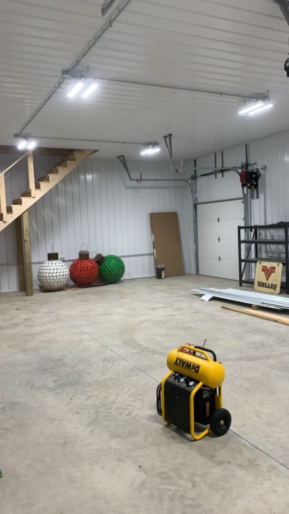 Shop interior wide view: stairs to loft, conduit and panel, sectional door, bright finish.