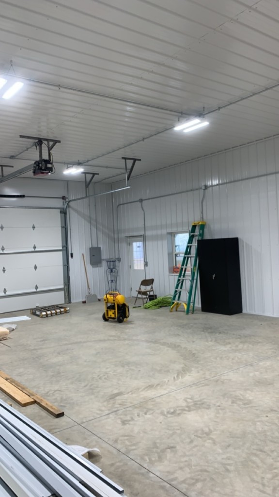 Ground-level shop: white metal walls and ceiling, sectional door, LED lighting, concrete floor.