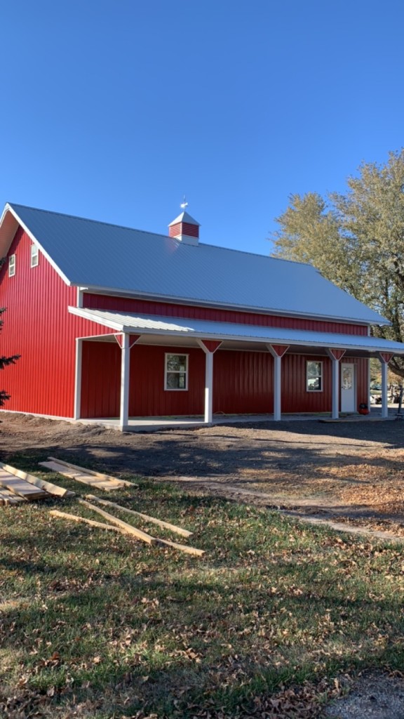 Same build: porch run, upper gable windows, red siding and white trim.